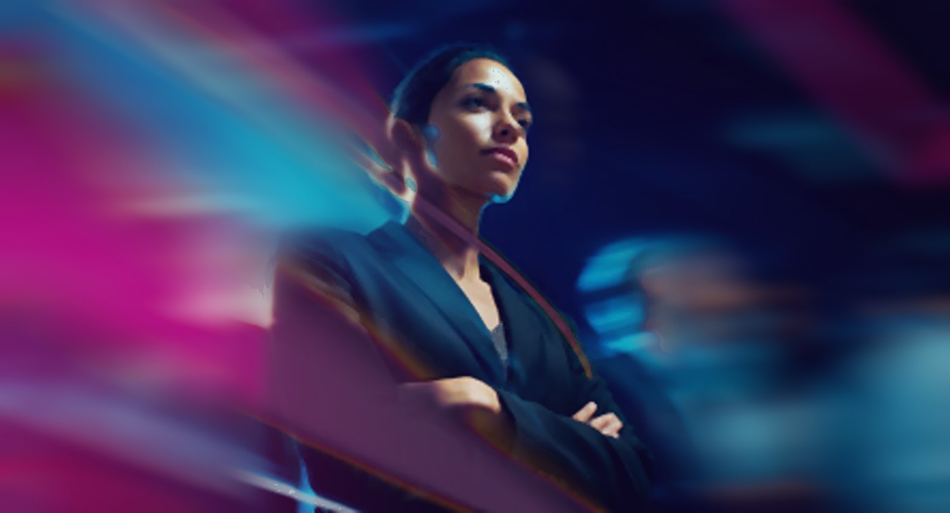 A woman with folded arms looks ahead, sharp and still, as streaks of pink and blue light rush past her